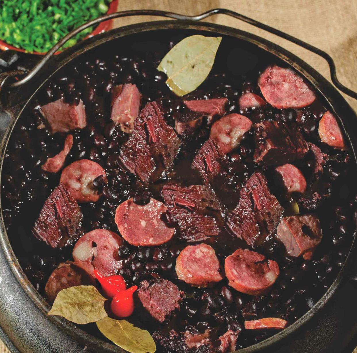 Feijoada completa servida em panela de barro com arroz, couve refogada, farofa e laranja — prato tradicional do Botequim Os Ximenes